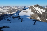 Z južného vrchola pokračujeme po južnom hrebeni do sedla medzi Finnan a Alnestind (v pozadí), odkiaľ lyžuje strmo doľava nadol na ľadovec